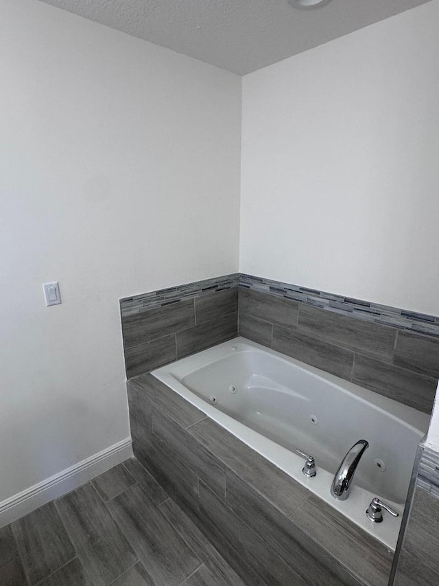 bathroom featuring tiled tub and a textured ceiling