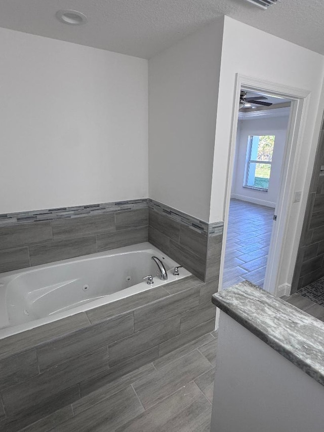 bathroom featuring tiled bath and a textured ceiling