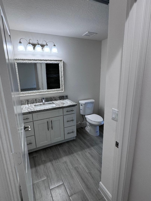 bathroom featuring vanity, a textured ceiling, and toilet