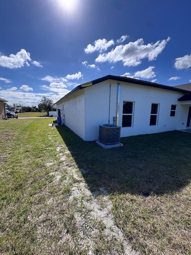 view of side of property with central AC and a lawn