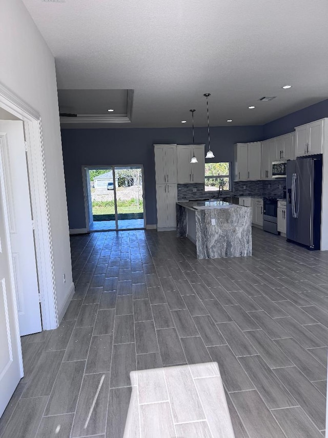 kitchen with a center island, plenty of natural light, appliances with stainless steel finishes, pendant lighting, and white cabinets