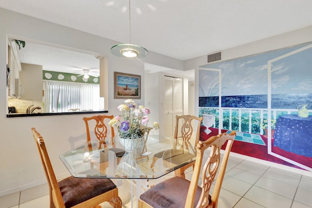 tiled dining area with ceiling fan and a textured ceiling