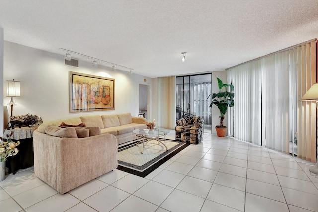 living room featuring rail lighting, light tile patterned floors, and a textured ceiling