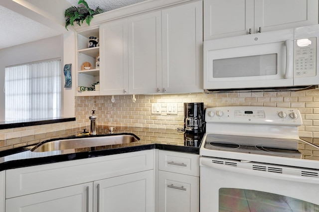 kitchen featuring sink, backsplash, white cabinets, and white appliances