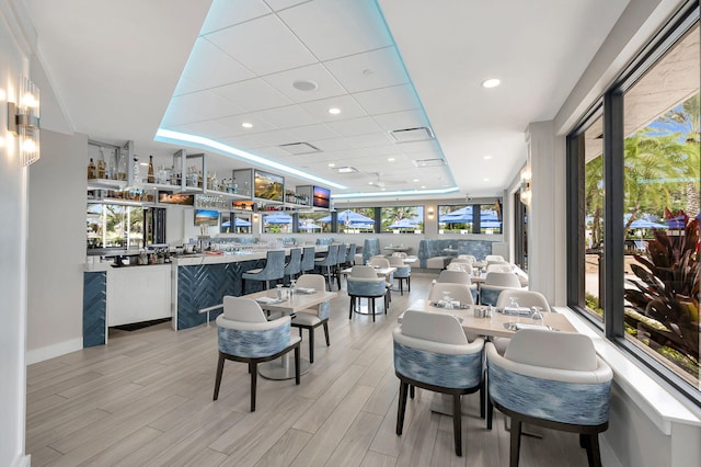 dining space featuring a raised ceiling and light hardwood / wood-style floors