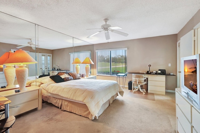 carpeted bedroom featuring french doors, ceiling fan, and a textured ceiling