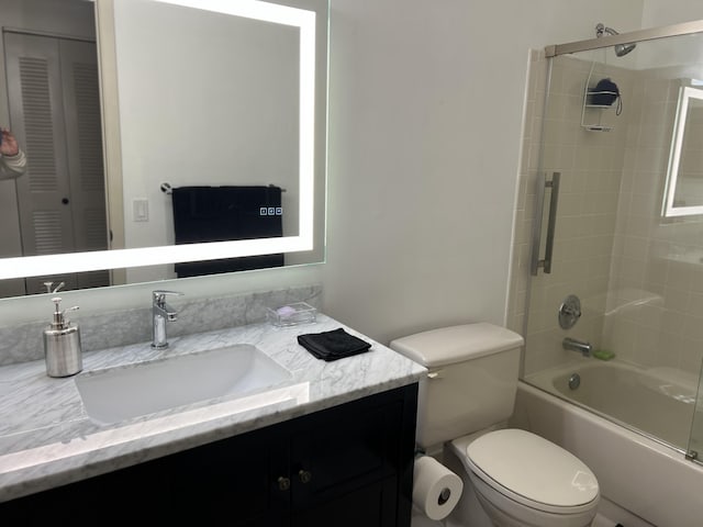 full bathroom with vanity, bath / shower combo with glass door, and toilet