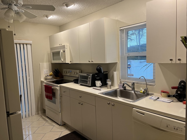 kitchen with light tile patterned flooring, sink, a textured ceiling, white appliances, and white cabinets