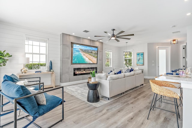 living room with a fireplace, light hardwood / wood-style floors, and ceiling fan