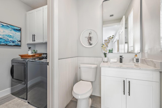 bathroom featuring independent washer and dryer, vanity, and toilet