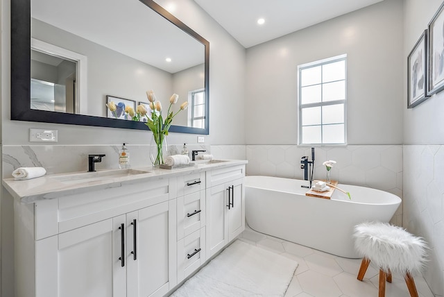 bathroom with vanity, a bathing tub, tile patterned flooring, and tile walls