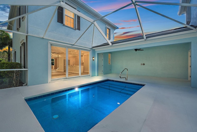 pool at dusk featuring a patio, ceiling fan, and glass enclosure