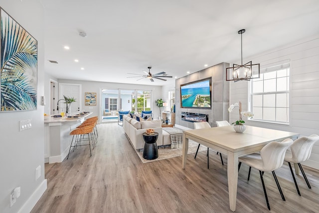 dining area with ceiling fan with notable chandelier and light hardwood / wood-style floors