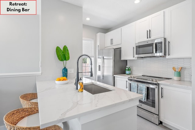 kitchen featuring white cabinetry, light stone countertops, kitchen peninsula, and appliances with stainless steel finishes