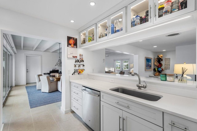 kitchen featuring light countertops, a sink, stainless steel dishwasher, and white cabinetry