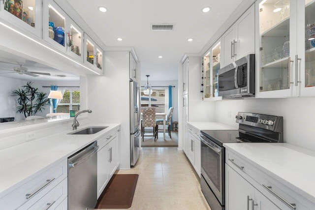 kitchen featuring stainless steel appliances, white cabinets, light countertops, and glass insert cabinets