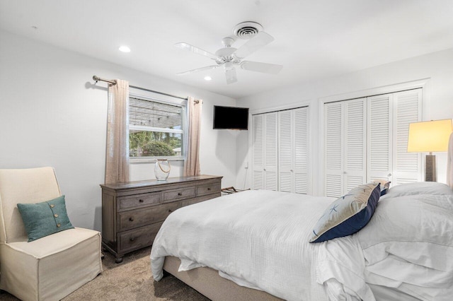 bedroom with two closets, recessed lighting, light colored carpet, visible vents, and ceiling fan