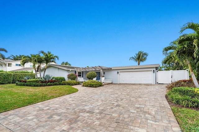 view of front of home with an attached garage, a gate, decorative driveway, a front lawn, and stucco siding