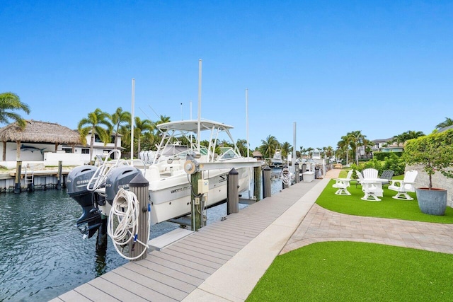 dock area with a water view, boat lift, and a lawn