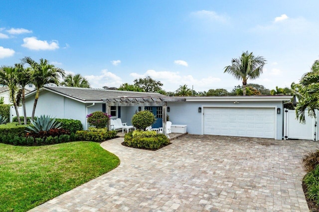 single story home featuring a front yard, decorative driveway, an attached garage, and stucco siding