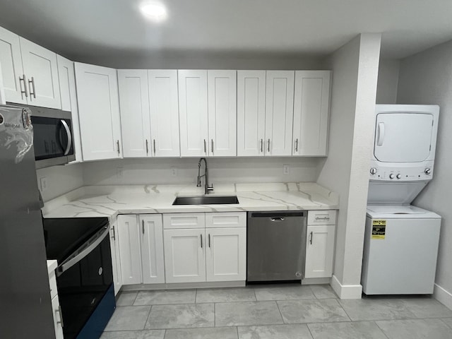 kitchen with sink, white cabinetry, stacked washer and dryer, and stainless steel appliances