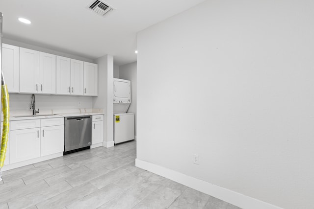 kitchen with stainless steel dishwasher, stacked washing maching and dryer, sink, and white cabinets