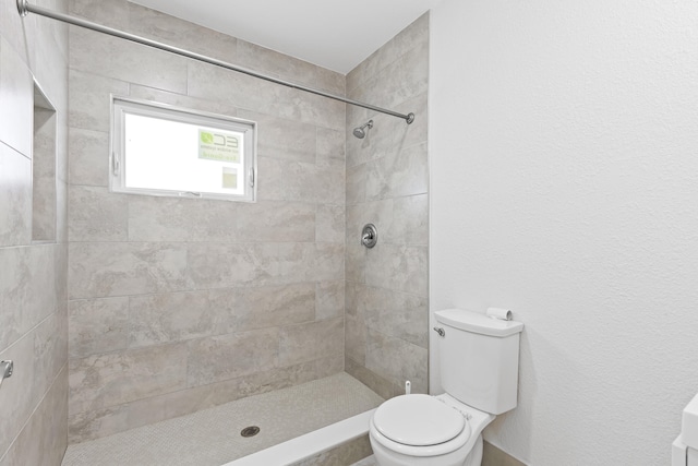 bathroom featuring a tile shower and toilet