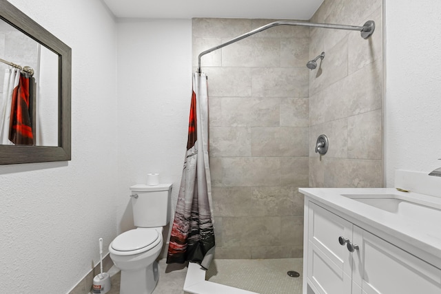 bathroom featuring vanity, toilet, and a tile shower