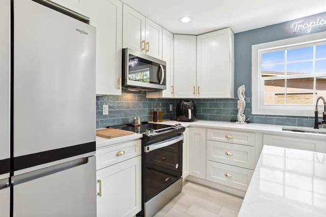 kitchen with sink, tasteful backsplash, white cabinetry, and stainless steel appliances