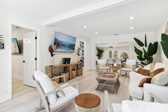 living room featuring beamed ceiling and light hardwood / wood-style floors