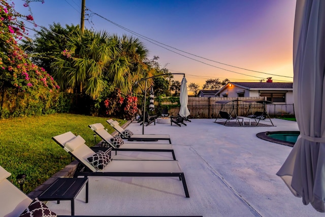 patio terrace at dusk with a fenced in pool and a lawn