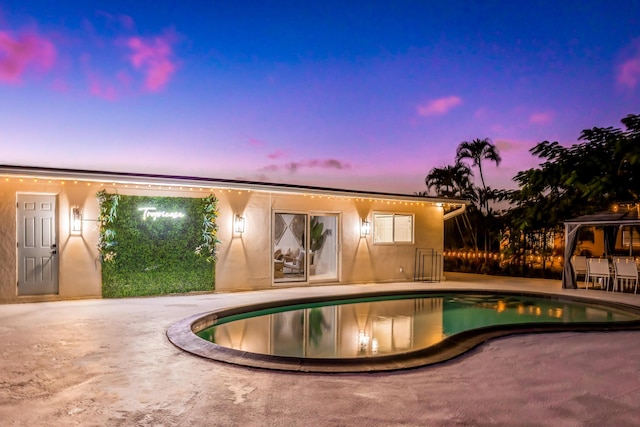 pool at dusk with a patio area