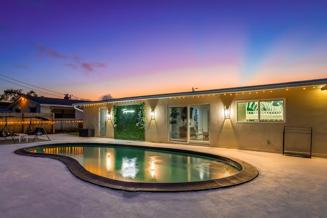 pool at dusk featuring a patio area