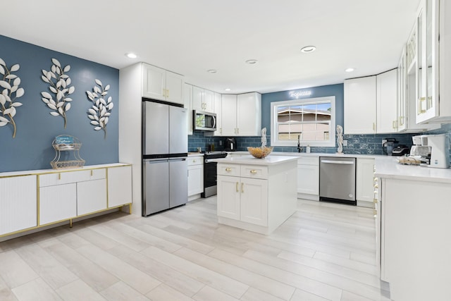 kitchen featuring white cabinets, a kitchen island, appliances with stainless steel finishes, and decorative backsplash