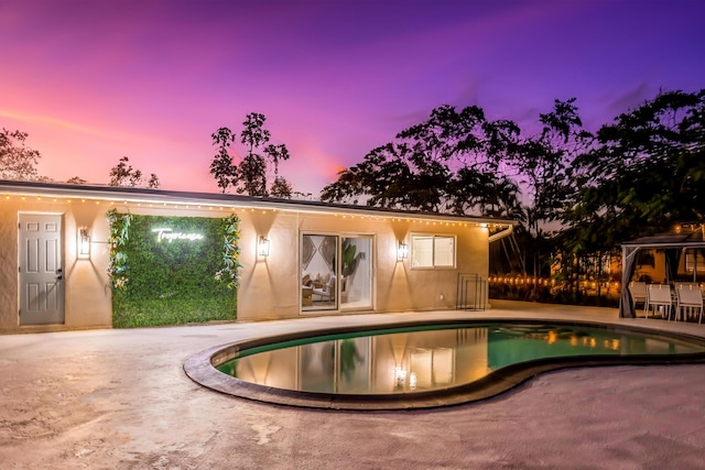 pool at dusk with a patio