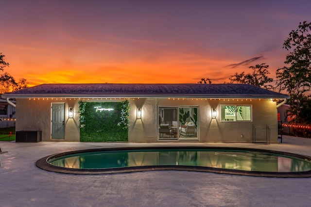 pool at dusk featuring a patio