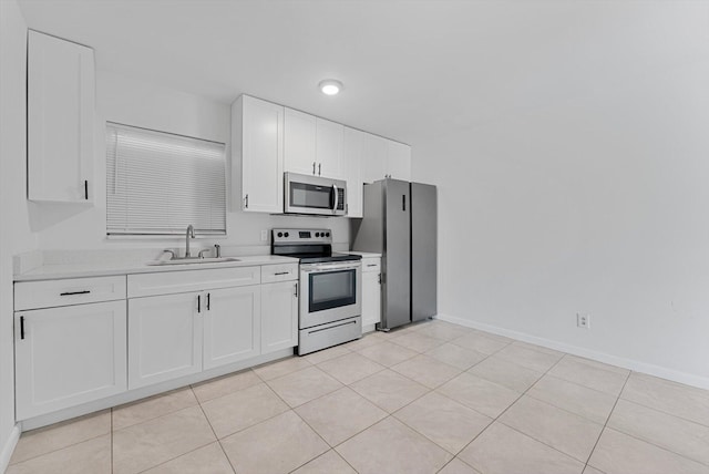 kitchen with light tile patterned floors, sink, white cabinets, stainless steel appliances, and light stone counters