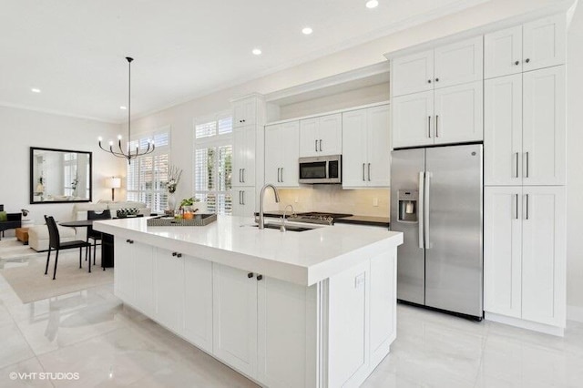 kitchen with white cabinetry, sink, hanging light fixtures, a kitchen island with sink, and stainless steel appliances