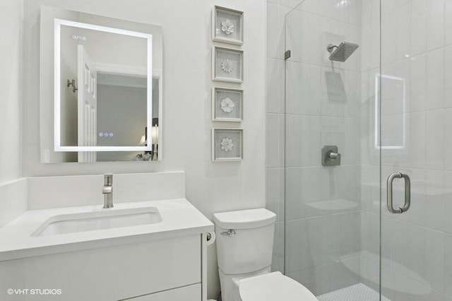 bathroom featuring vanity, toilet, and a shower with shower door