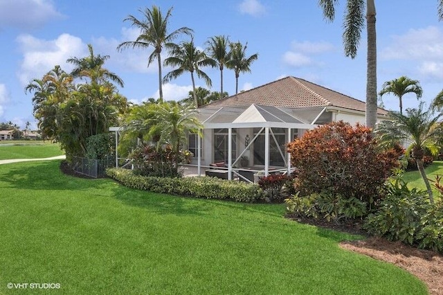 rear view of house with a yard and a lanai