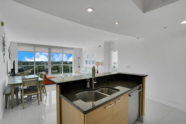 kitchen with sink, dishwasher, a center island with sink, light tile patterned flooring, and dark stone counters