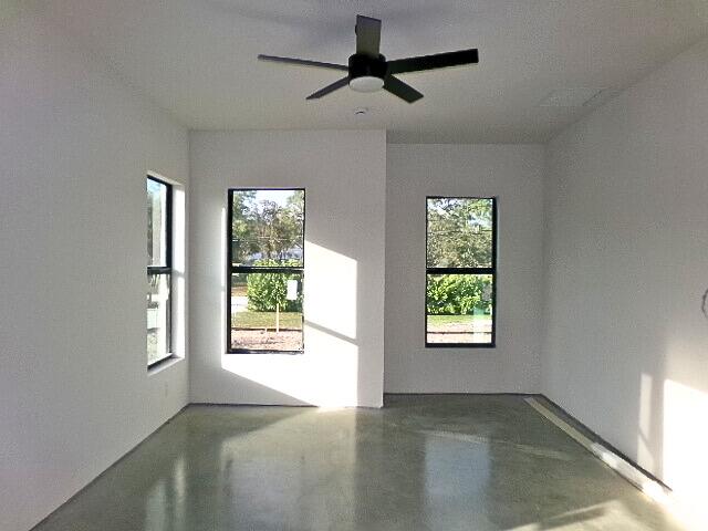 unfurnished room featuring ceiling fan and concrete floors