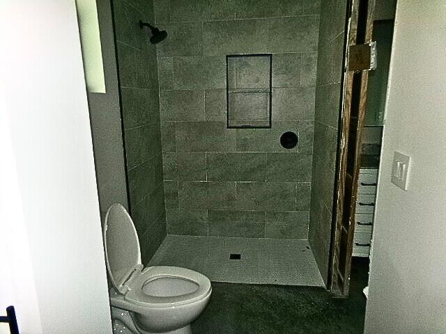 bathroom featuring a tile shower and toilet