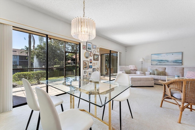 dining area featuring a water view, light colored carpet, a chandelier, and a textured ceiling