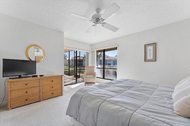 carpeted bedroom with a textured ceiling, access to outside, and ceiling fan