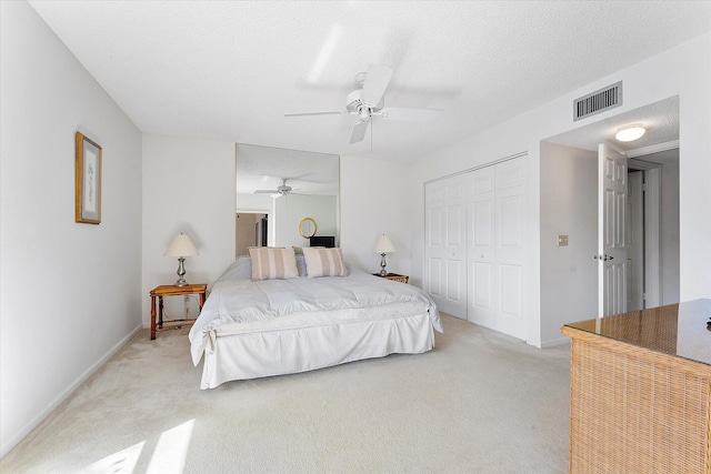 carpeted bedroom featuring ceiling fan, a closet, and a textured ceiling