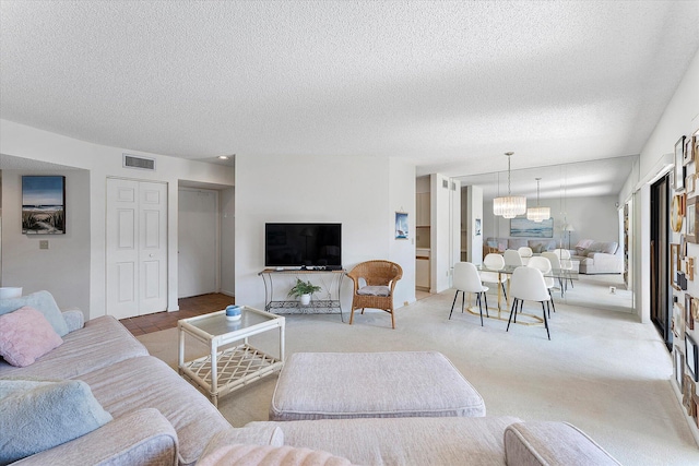 living room with light colored carpet, a textured ceiling, and an inviting chandelier