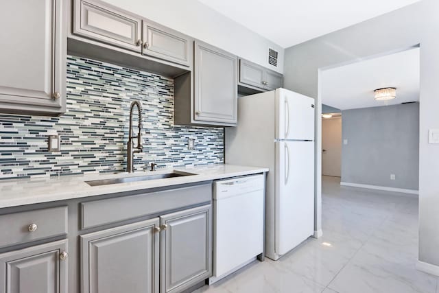 kitchen featuring sink, gray cabinetry, light stone counters, dishwasher, and backsplash