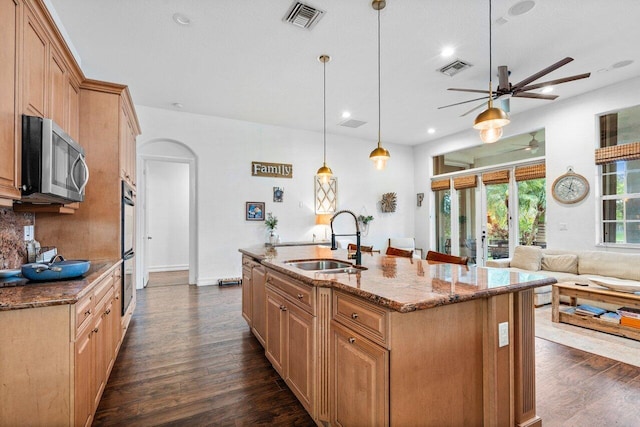 kitchen with sink, an island with sink, hanging light fixtures, and stainless steel appliances