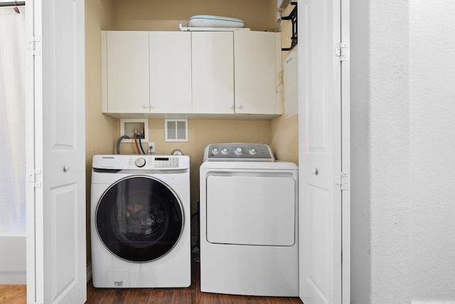 laundry area featuring washing machine and clothes dryer, dark hardwood / wood-style floors, and cabinets